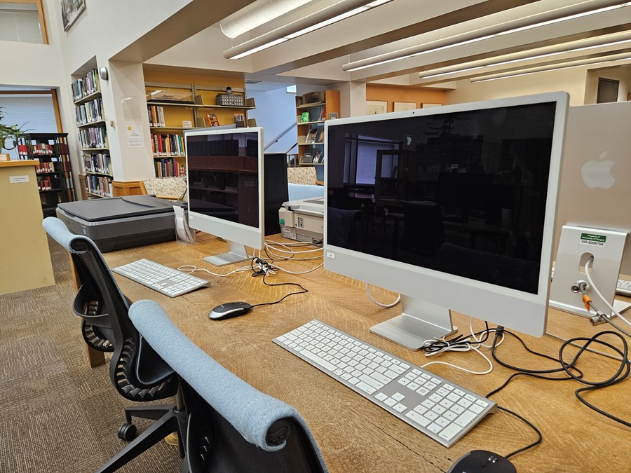 Wide view of two computer stations in the Lawrence Room 200 Design Library computer lab. The computer lab stations are equipped with a larger scanner.