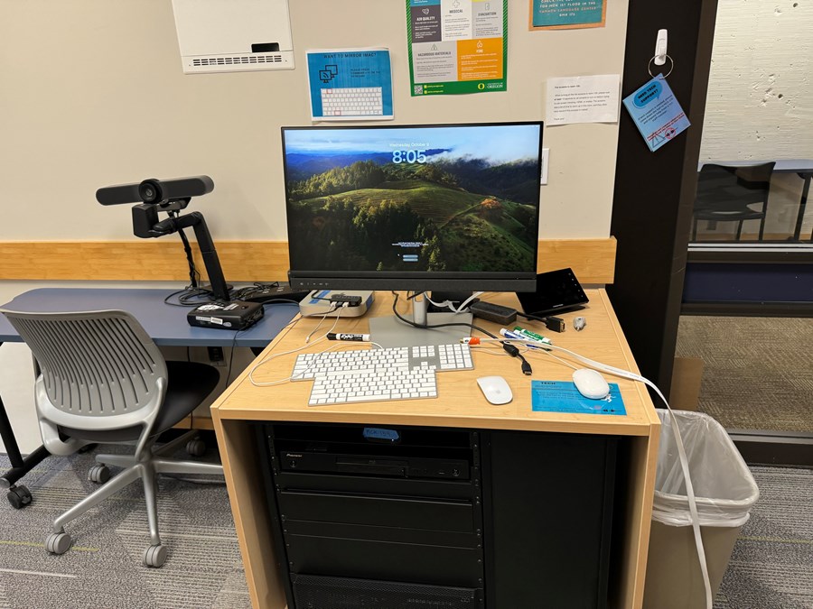 Computer on a desk with a whiteboard in the background