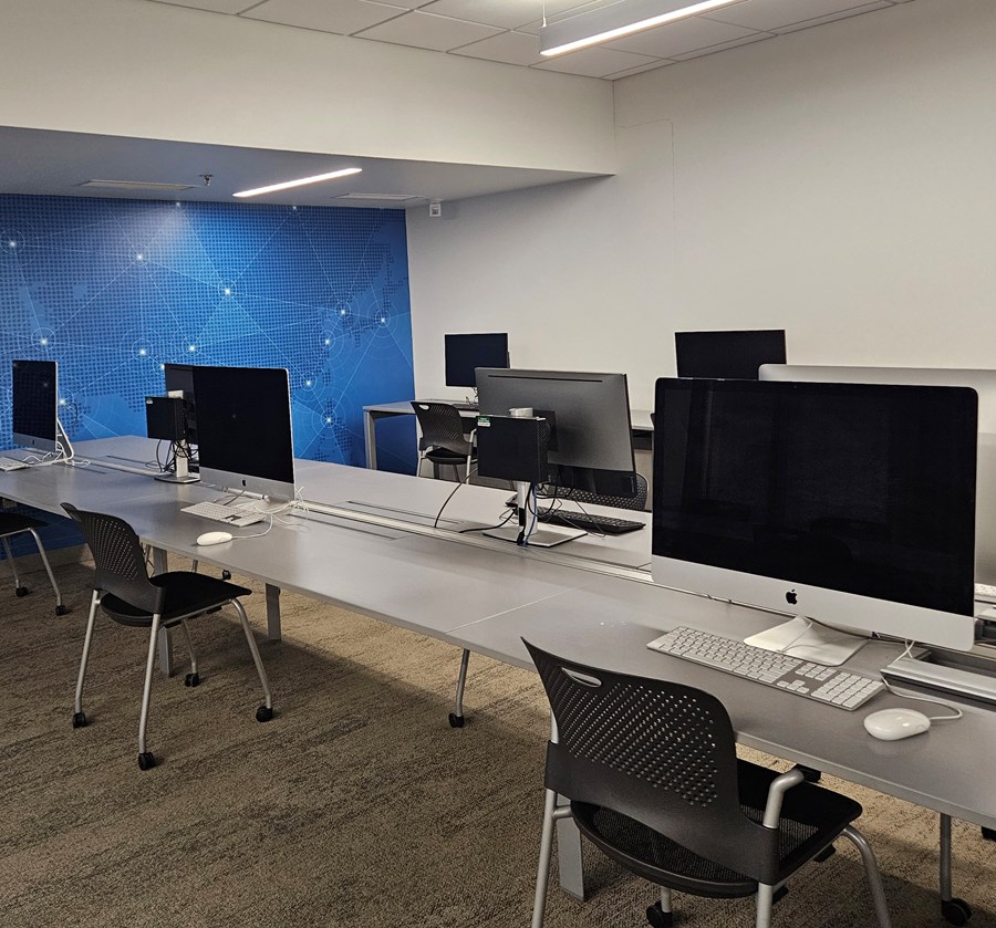 Wide view of three long desks equipped with computer stations.