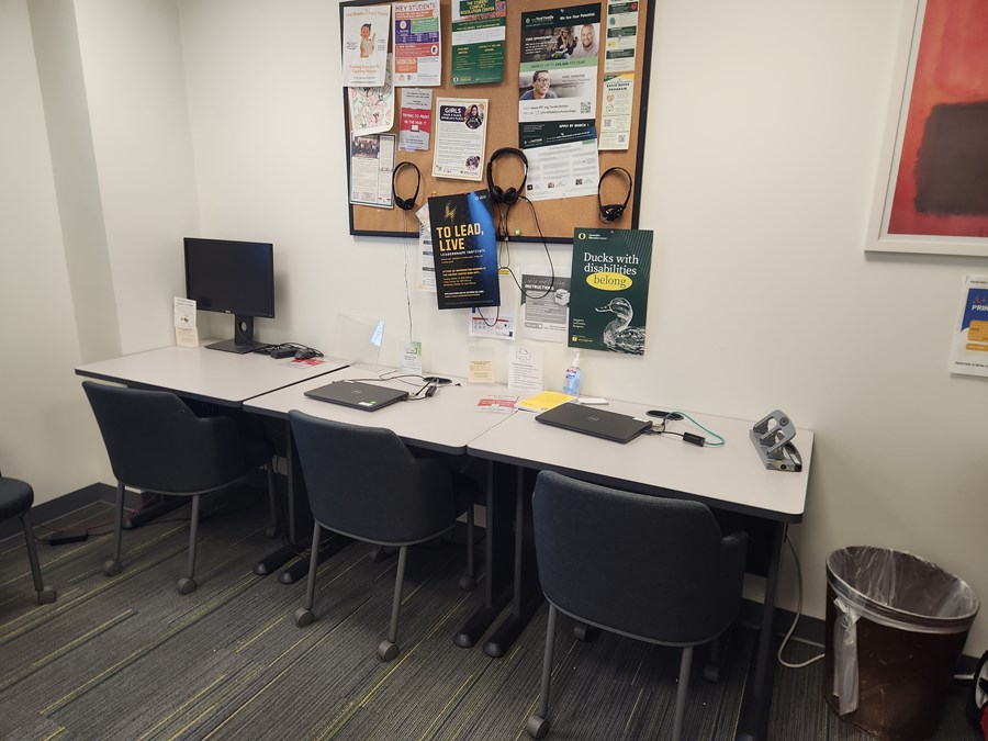 TRIO laptops on a table with a bulletin board above on the wall