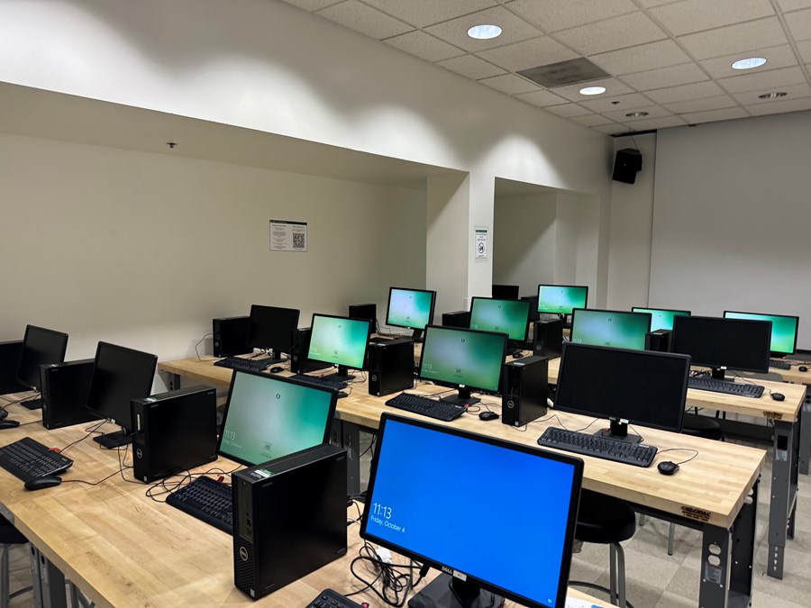 Lawrence 100: computers on desks with a projector screen on the far wall