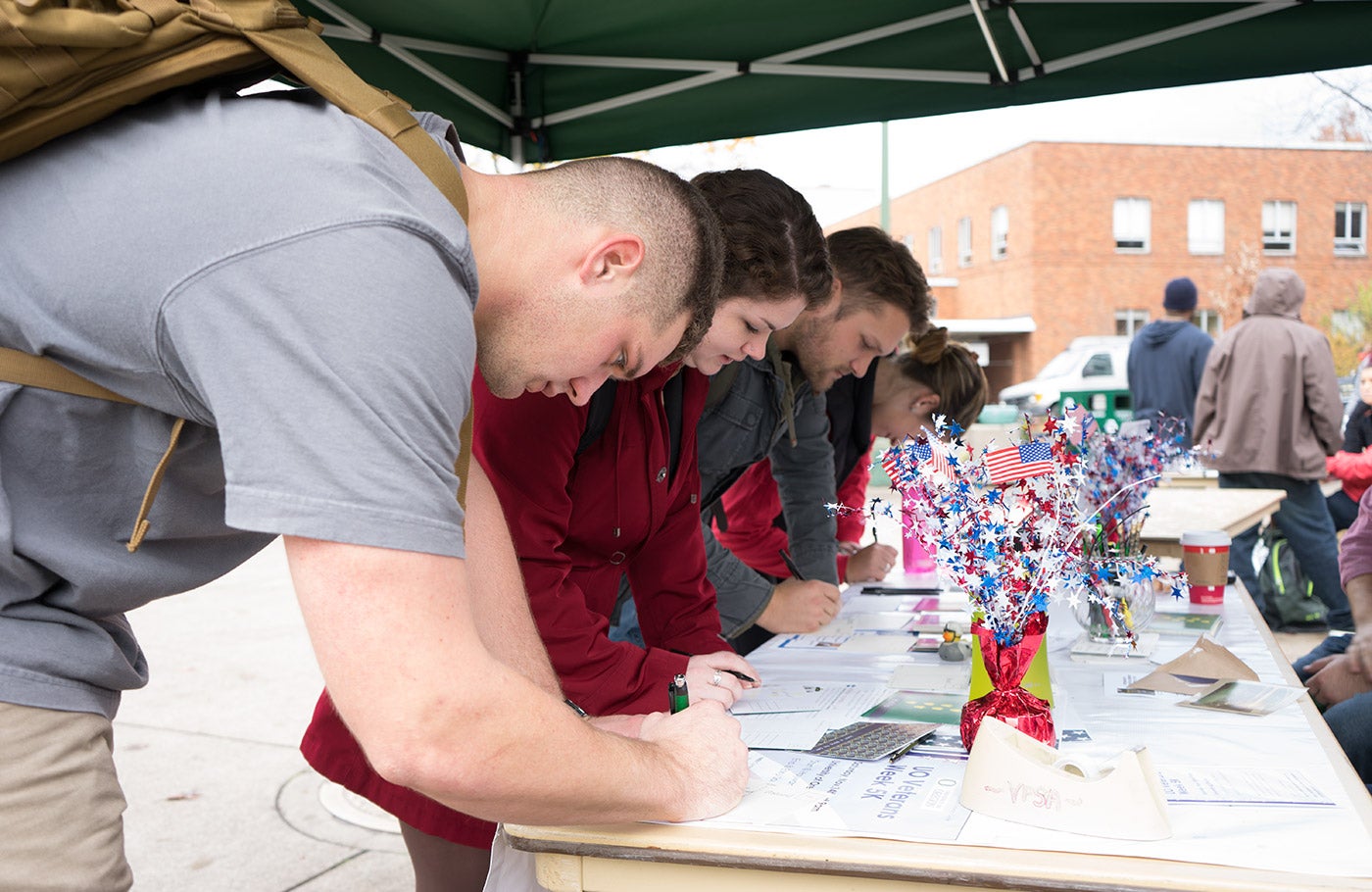 A student veteran signs a postcard to send to soldiers overseas during Veterans Day.