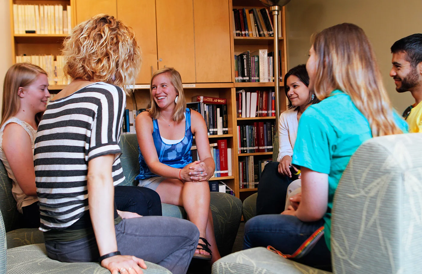 Six people circled in meeting space conversing with one another.