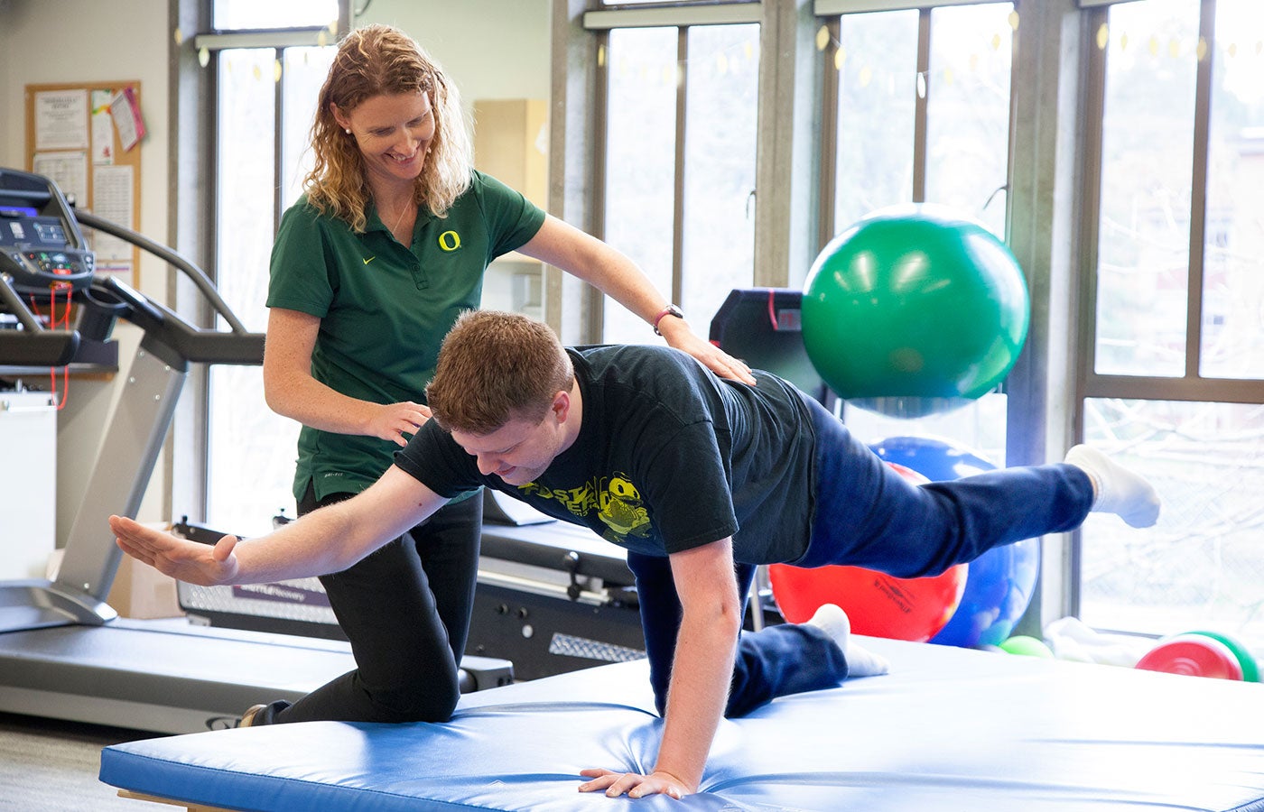 A physical therapist guides a student through a physical therapy exercise.